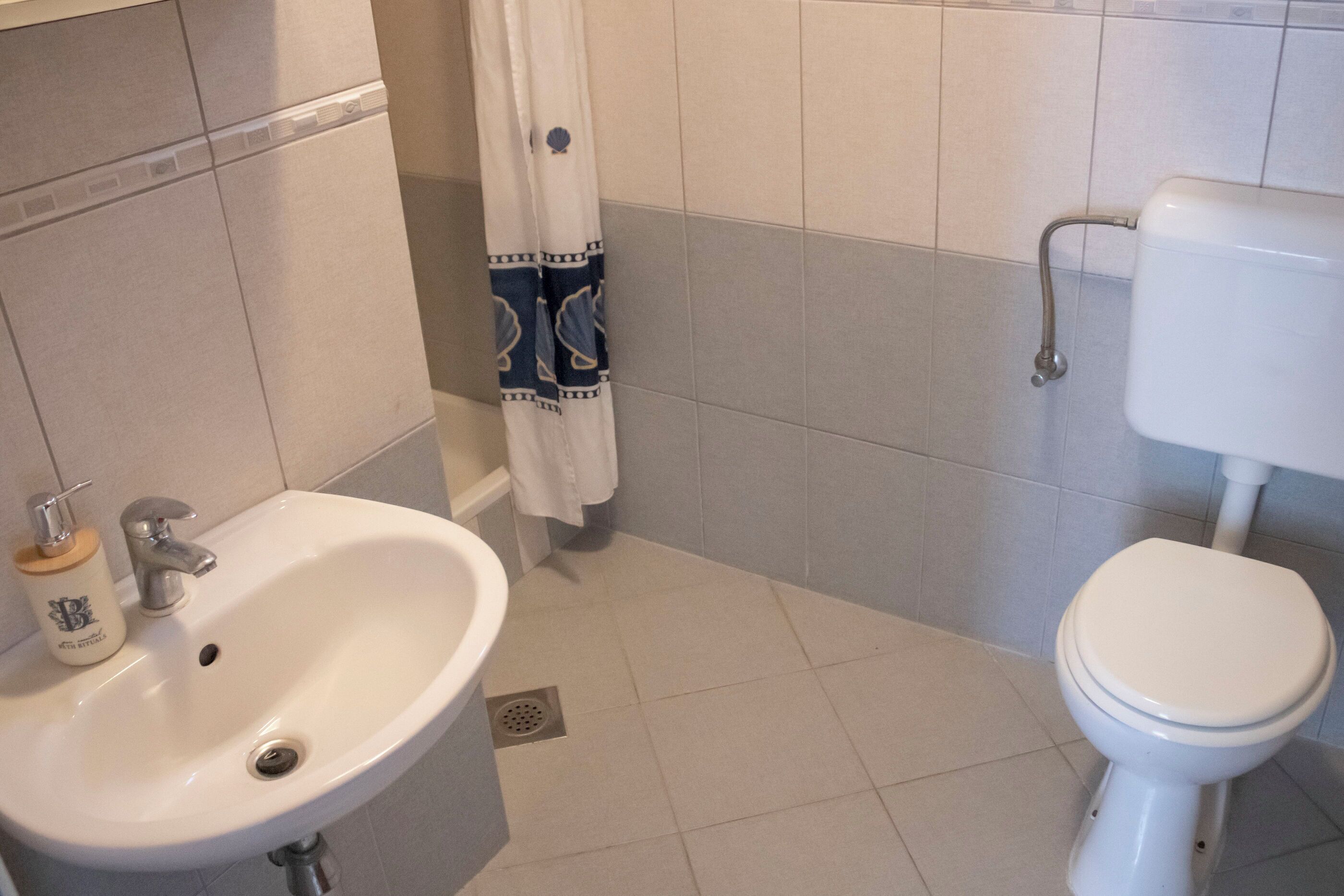 Un baño con lavamanos blanco, inodoro y cortina de ducha.