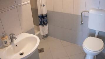 Un baño con lavamanos blanco, inodoro y cortina de ducha.