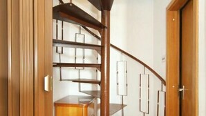 Una scala a chiocciola con finitura in legno e ringhiere in metallo, che conduce a un piano superiore.