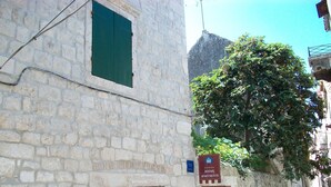 A stone building with a sign indicating "ROOMS APARTMENTS" and a tree in front. - Apartment and Room Ivica (Trogir)