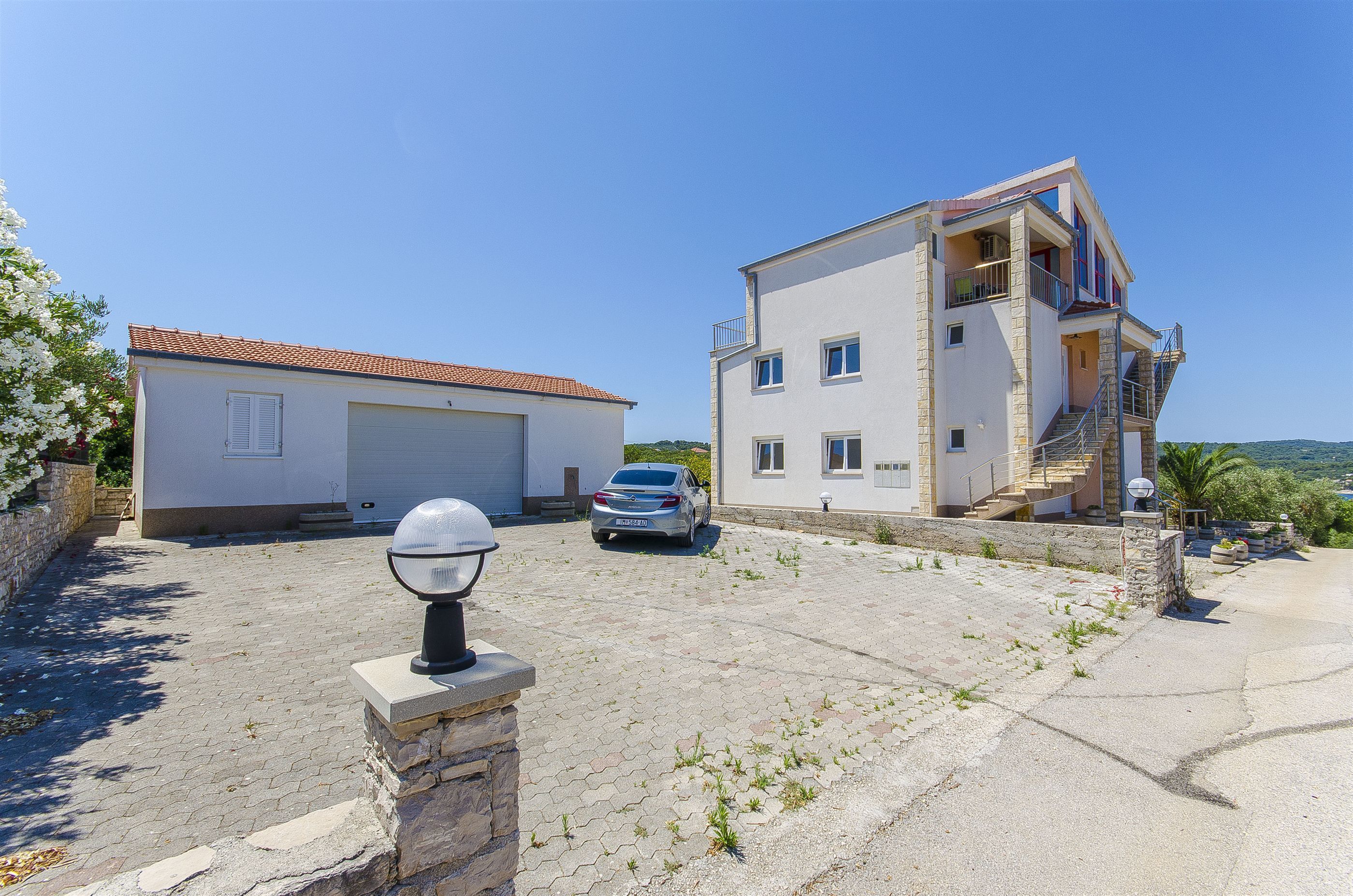 Ein zweistöckiges Haus mit Garage, ein Auto davor und einem strahlend blauen Himmel.