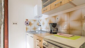 Una cucina compatta con piano cottura, lavandino e macchina per il caffè.