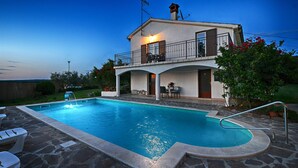 Una casa a due piani con piscina, mobili da esterno e un balcone con ringhiera.
