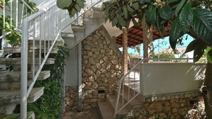 A staircase with stone walls and white railings, surrounded by greenery.