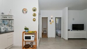 A modern kitchen with a microwave, kettle, and a small wooden shelf with kitchen utensils.