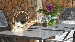 A table with a woven basket containing a bottle and a glass, and a vase with flowers.