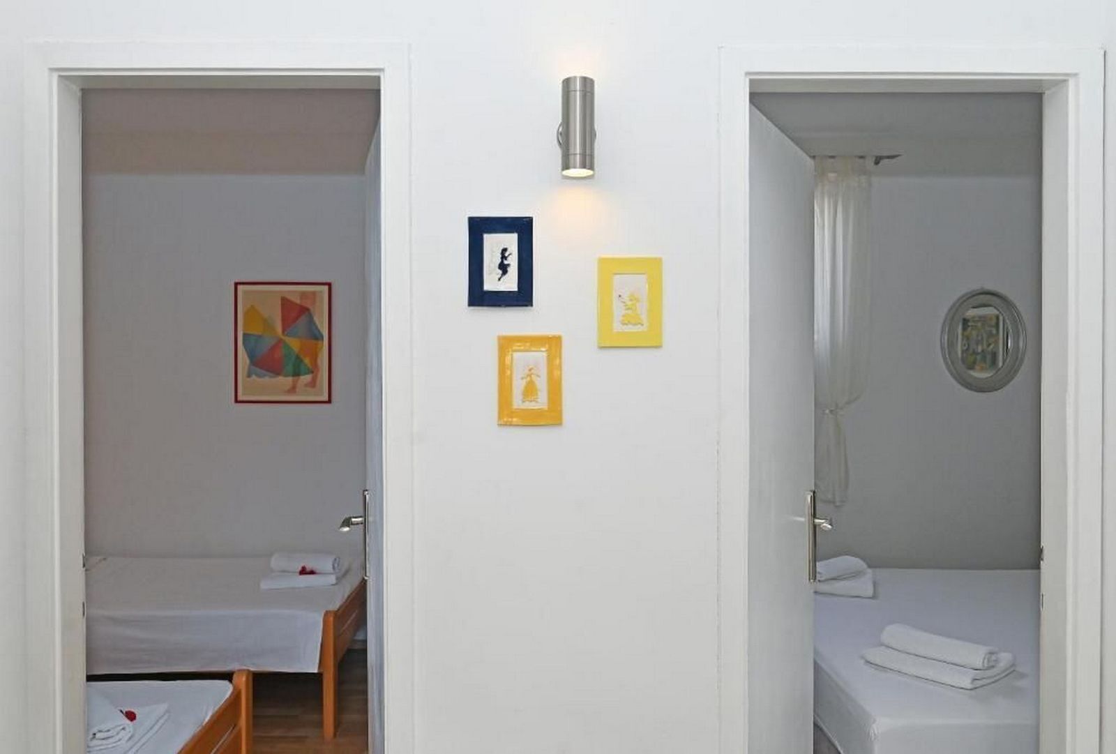 Une chambre d’hôtel avec deux lits, une petite table et trois tableaux encadrés accrochés au mur.