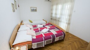 A bedroom with a wooden bed, a patterned bedspread, and a small bedside table with a lamp. - Apartment Zlatko (Pirovac)