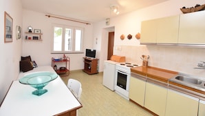 A compact kitchen with a stove, sink, and a glass bowl on the counter. - Apartments Ziva (Primosten)