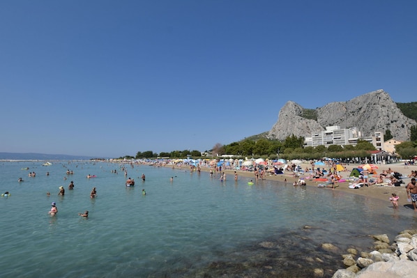 Une plage Ă lâeau claire, avec un rivage rocheux et une montagne en arriĂšre-plan.