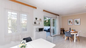Un salon moderne comprenant un coin repas, un réfrigérateur blanc, un four à micro-ondes et une table à manger avec des chaises.