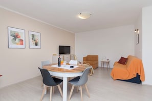 Uma sala de estar moderna com área de jantar, sofá e televisão.