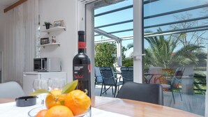Un coin repas avec une table dressée pour deux personnes, une bouteille de vin et un saladier rempli d’oranges.