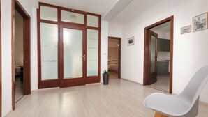 Une pièce avec une armoire en bois, une chaise grise et une plante en pot.