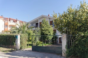 A residential building with a gated entrance, a balcony, and a well-maintained garden. - Apartments and Rooms Antee (Vodice)