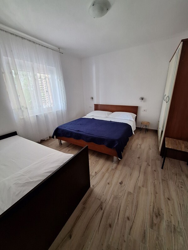 Une chambre à coucher comprenant un lit, une table de chevet, une armoire et une fenêtre avec des rideaux.