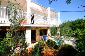 Un bâtiment à deux étages doté d’un balcon, d’une façade en pierre et d’un espace piscine.
