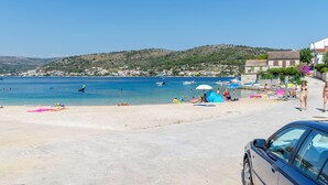 A beach with clear blue water, a few boats, and people enjoying the sun.