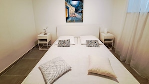 Ein Hotelzimmer mit einem großen Bett, zwei Nachttischen, einem Beistelltisch und einem Bild an der Wand.
