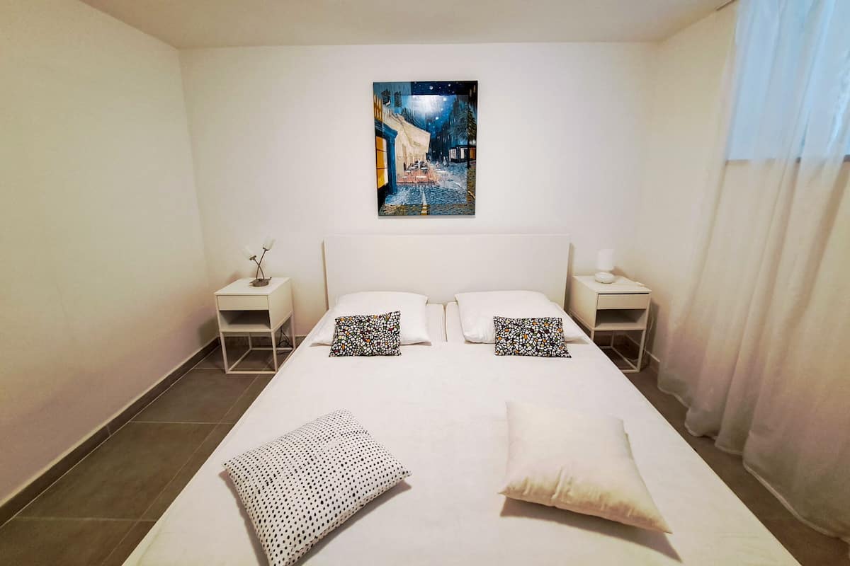 Een hotelkamer met een groot bed, twee nachtkastjes, een wandlamp en een schilderij aan de muur.