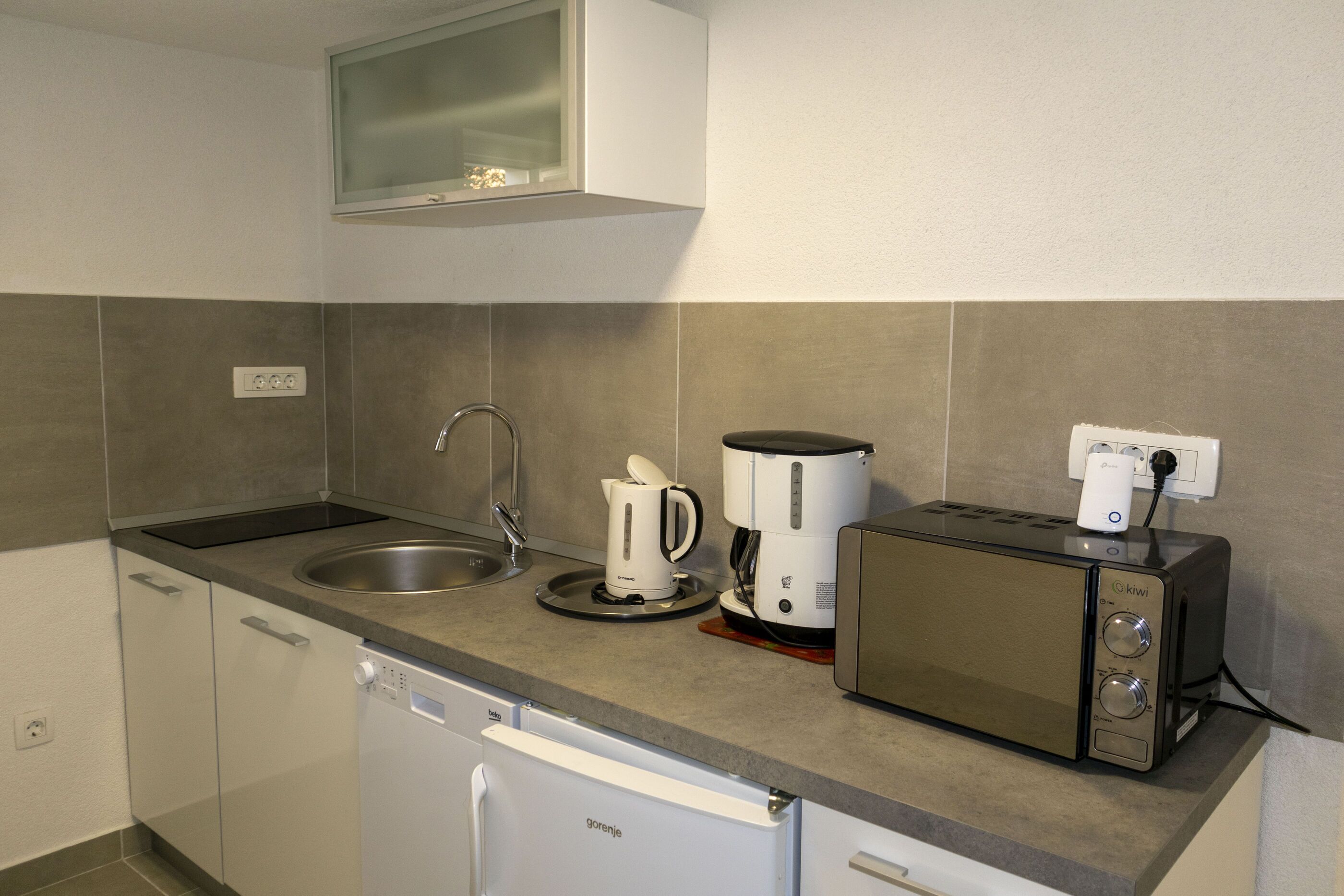 A compact kitchen with a dishwasher, a coffee maker, and a toaster.