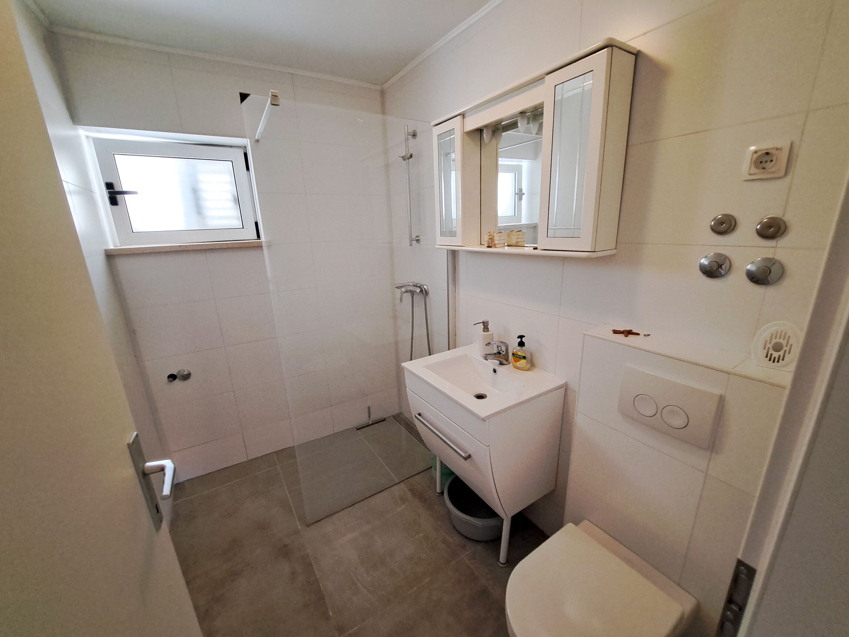Une petite salle de bain propre, équipée de toilettes, d’un lavabo et d’une douche.