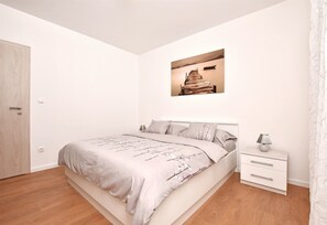 A bedroom with a bed, a nightstand, a wall-mounted picture, and a door. - Apartment Dora (Duce)