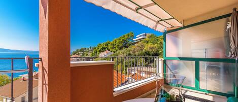 A balcony with a clear view of the sea and a hillside.