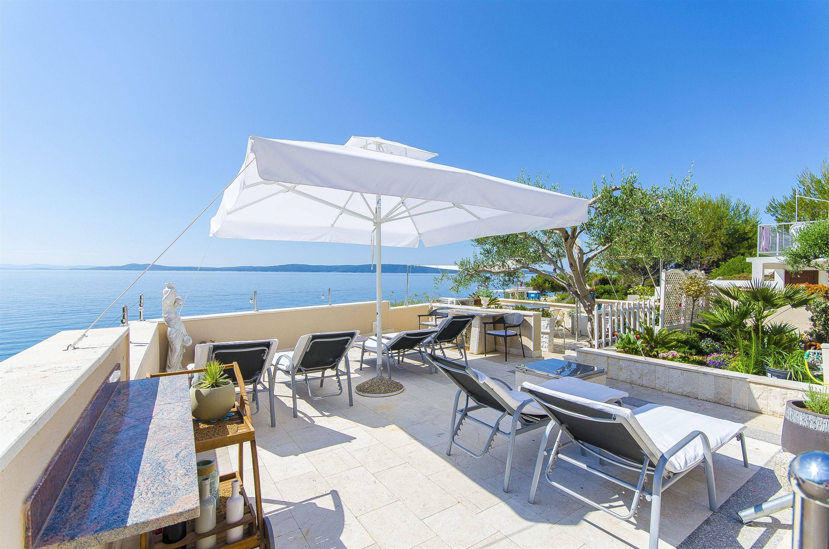Eine Terrasse mit Sitzgelegenheiten im Freien, einem Tisch und einem großen Sonnenschirm.