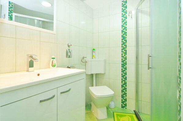 A bathroom with a white sink, toilet, and shower. - Apartment Steli (Slatine)