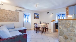 Ein gemütliches Zimmer mit einem Bett, einem Esstisch mit Stühlen, einer Küchenzeile und einer Steinwand.