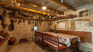 Ein rustikaler Raum mit Steinwänden, Holzbänken und einem Tisch, der mit einer blumigen Tischdecke bedeckt ist.