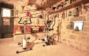 A rustic room with a stone wall, a wooden door, and a shelf with various items. - House Marta (Omis)