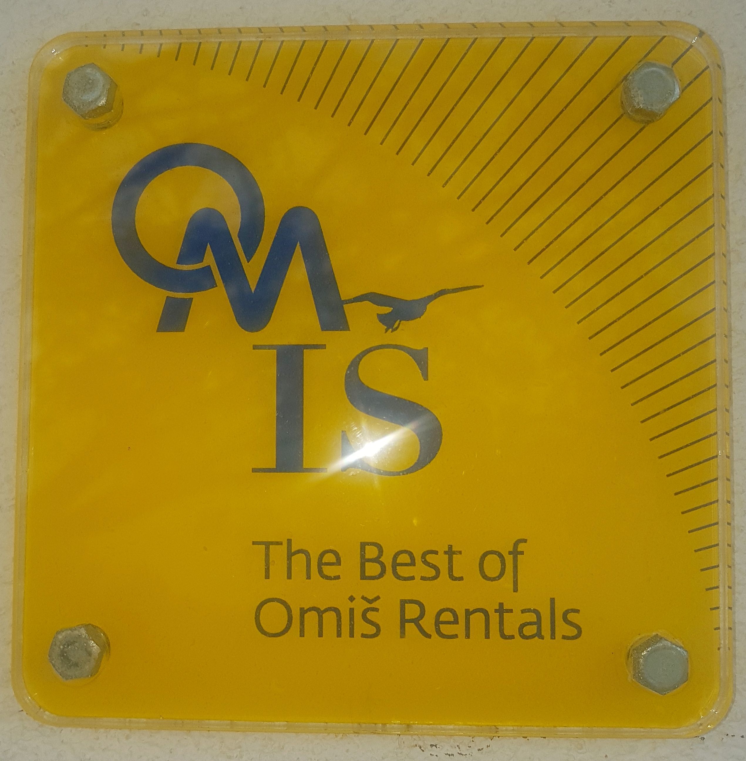 Un panneau jaune portant le logo « OMIS » et le texte : « Le meilleur des locations à Omiš ».