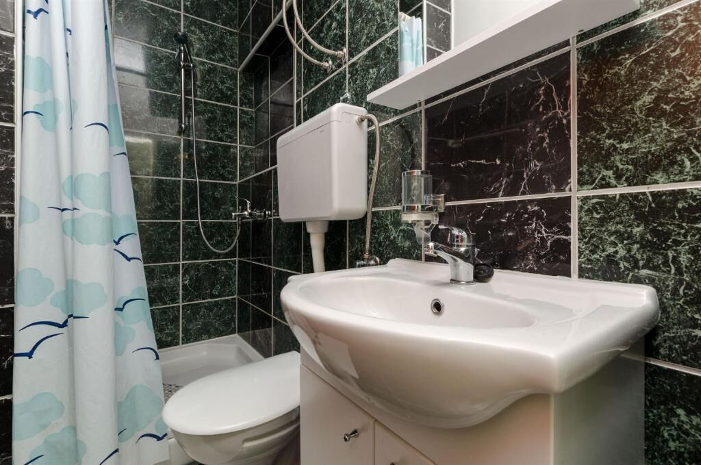 A bathroom with a white sink, toilet, and shower curtain.