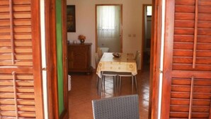 A dining area with a table set for four, a cabinet, and a chair. - Apartment Tomislav (Okrug Gornji)