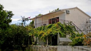 A single-story building with a balcony, surrounded by greenery. - Apartment Tomislav (Okrug Gornji)
