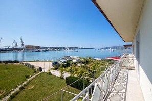 A balcony with a view of a marina and boats, a grassy area, and a clear sky. - House Ivica (Seget Donji)