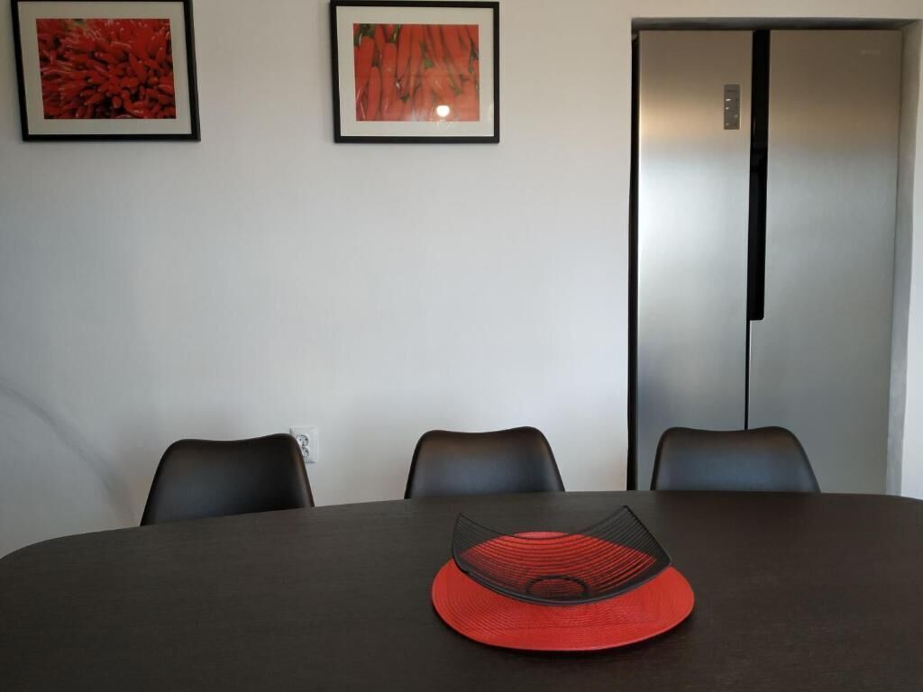 A conference room with a dark table, three chairs, and two framed pictures on the wall.