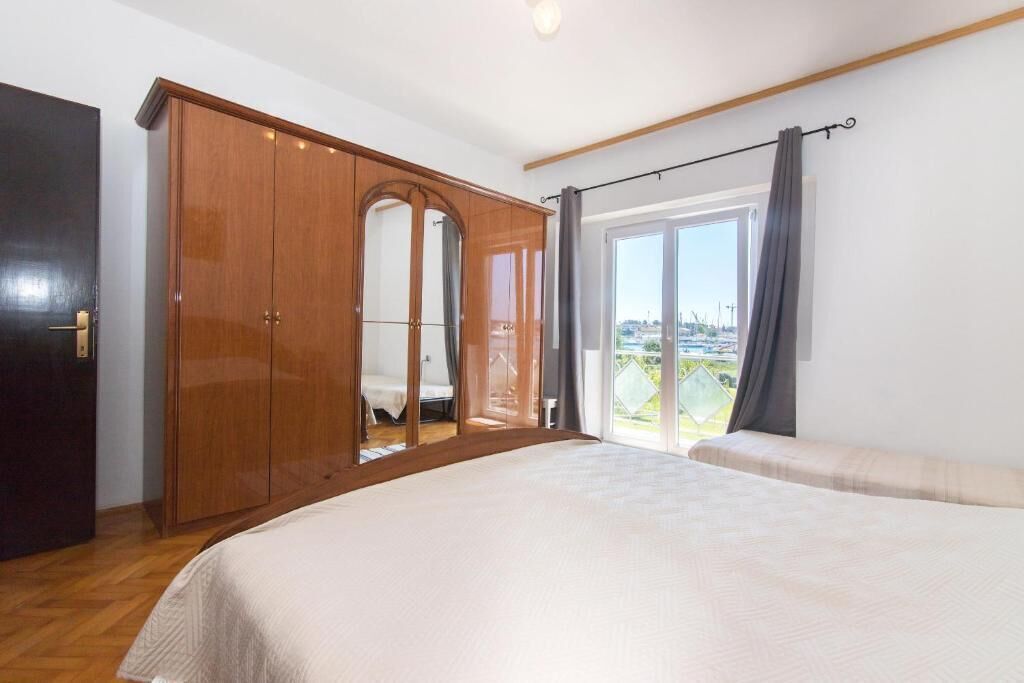 A bedroom with a large bed, a wardrobe, and a sliding glass door leading to a balcony.