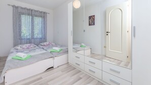 A bedroom with two beds, a large mirror, and a wardrobe. - Apartment Josipa (Omis)