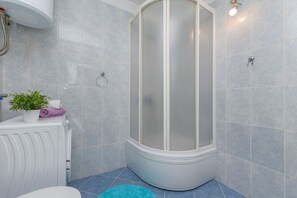 A bathroom with a shower enclosure, a radiator, and a potted plant. - Apartment Josipa (Omis)