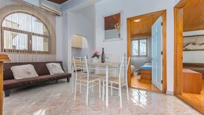 A modern living room with a sofa, dining table, chairs, and a view into another room. - Apartment Dorijana (Porec)