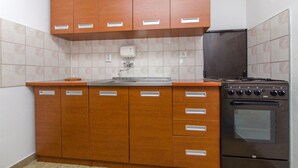 A kitchen with wooden cabinets, a stainless steel sink, and a black oven. - Apartment Vojka (Vrbanj)