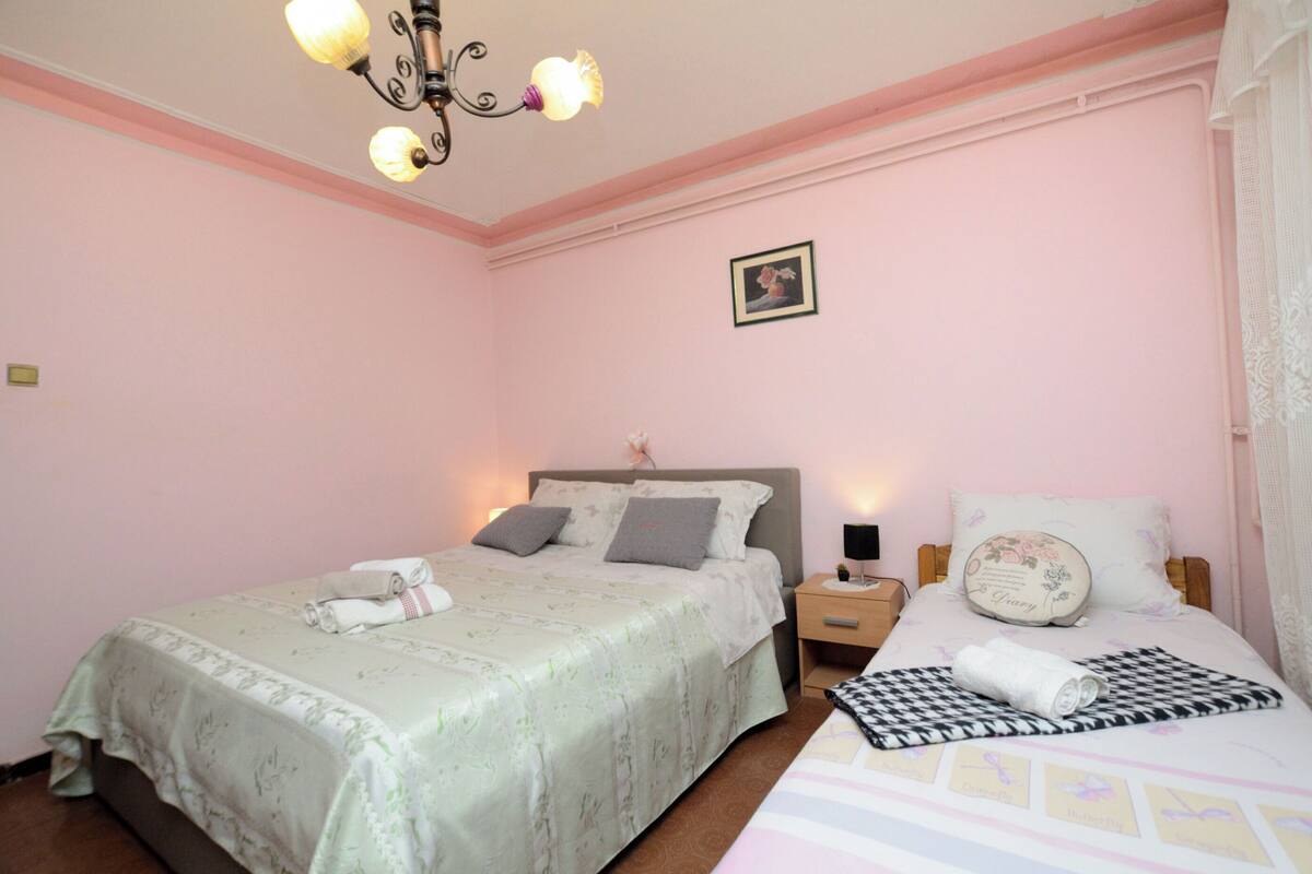 Une chambre avec deux lits, un lustre et une petite table de chevet avec une lampe.