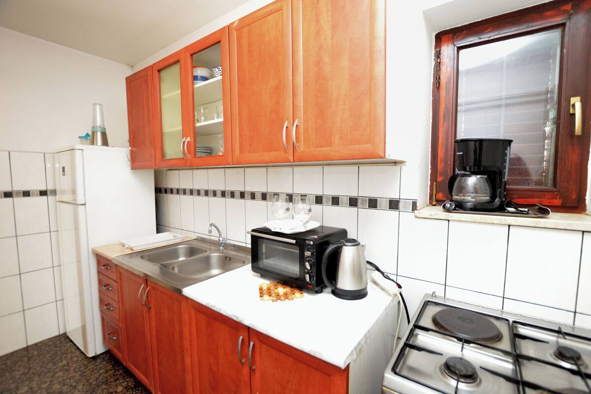 Une cuisine équipée de meubles en bois, d’un four à micro-ondes, d’un grille-pain, d’une bouilloire, d’une machine à café et d’une cuisinière.