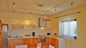 A compact kitchen with a dining area, equipped with a refrigerator, microwave, sink, and stove. - Apartment Mario (Sumartin)