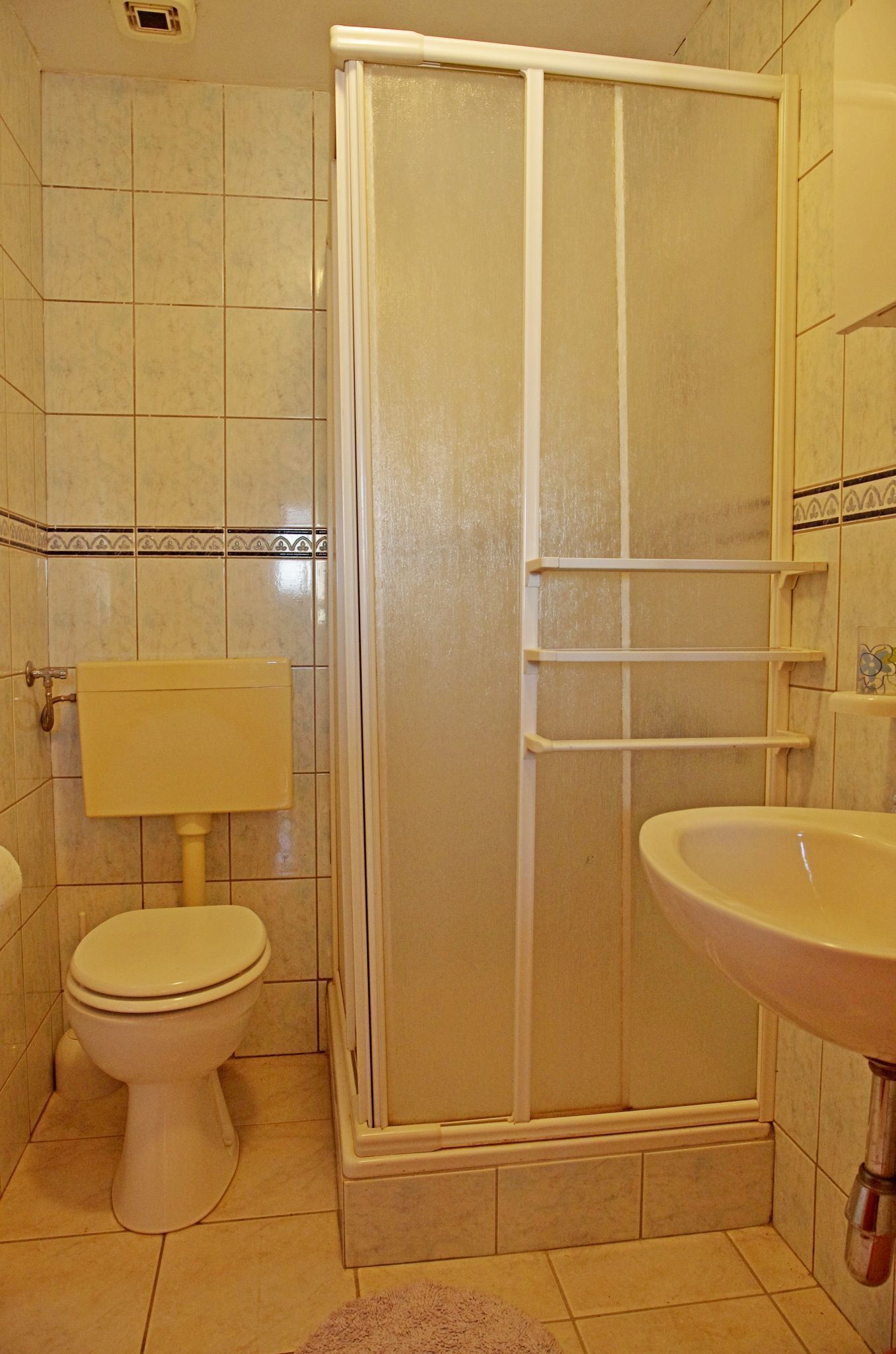 Uma casa de banho com sanita, cabine de duche e lavatório.