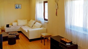 A living room with a sofa, a coffee table, a TV, and a wooden cabinet. - Apartment Mario (Sumartin)