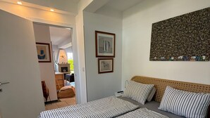 A bedroom with a large bed, a headboard, and a wall-mounted artwork. - Apartment Vito (Njivice)